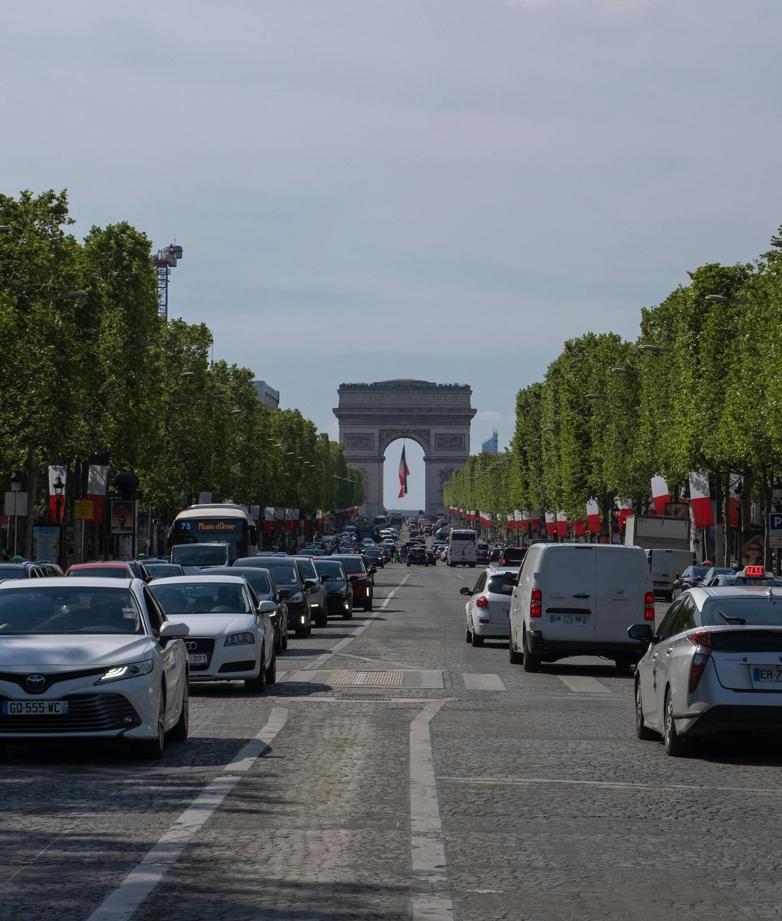 Cars are driving down a street in front of the Arc de Triumph