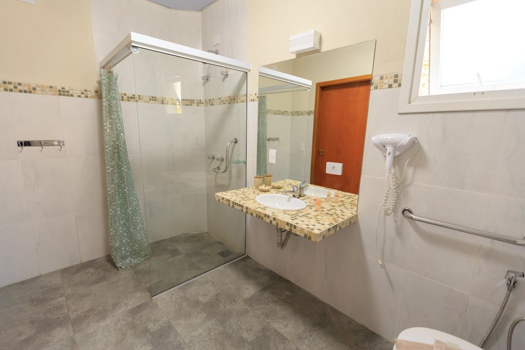 Spacious and accessible bathroom featuring a large glass shower, modern sink, and grab bars.