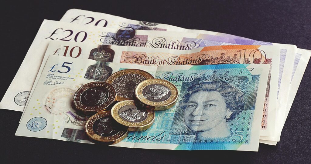 High-quality image of British pound notes and coins on a dark surface, showcasing currency detail.